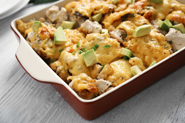 Roasted chicken with cheese in casserole dish on kitchen table