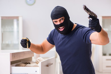 Robber wearing balaclava stealing valuable things