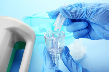 Doctor filling medication cup with remedy for inhalation therapy