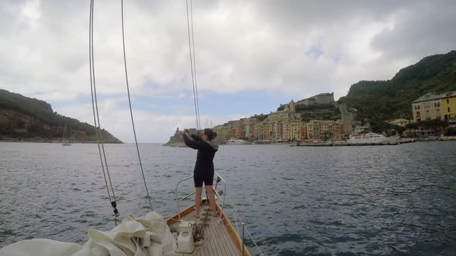 Travel woman taking photos of Italy coast with smart phone technology from luxury sailboat for social media sharing 