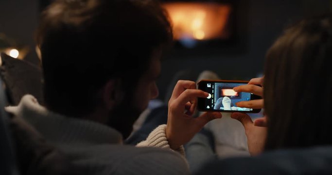 Closeup of couple using digital tablet by fireplace taking photos fire social media sharing on digital device