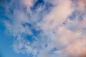 Obraz premium White pink fluffy clouds on blue sky