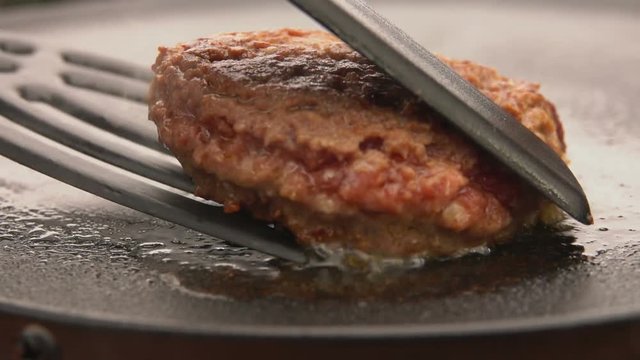 Burger flipped on the stone grill with kitchen spatula