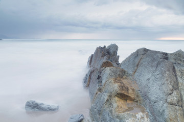 Serene seascape in Arrietara beach, Biscay, Basque Country, Spain. Long exposure on a cloudy sunset.