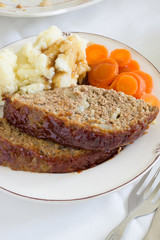 Classic American meatloaf made with ground beef with mashed potaotes and carrot coins