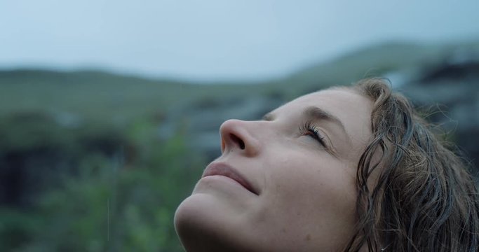 Close up portrait of Woman looking up at rain in nature with wet hair  Hiker Girl trekking in Scotland Slow Motion