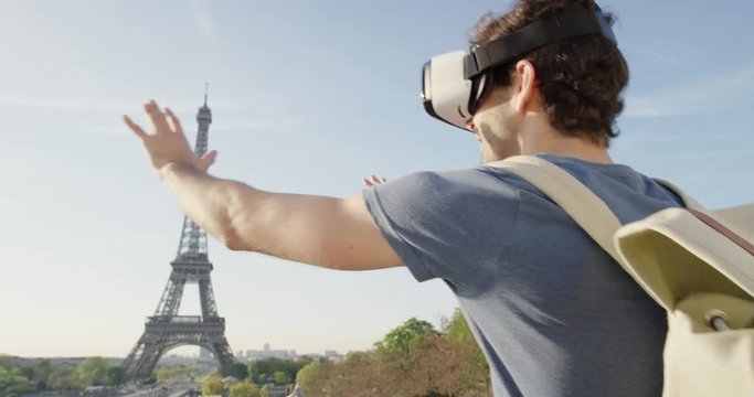 Tourist Man wearing virtual reality headset looking at Eiffel Tower Paris watching 360 video imagination concept at sunset