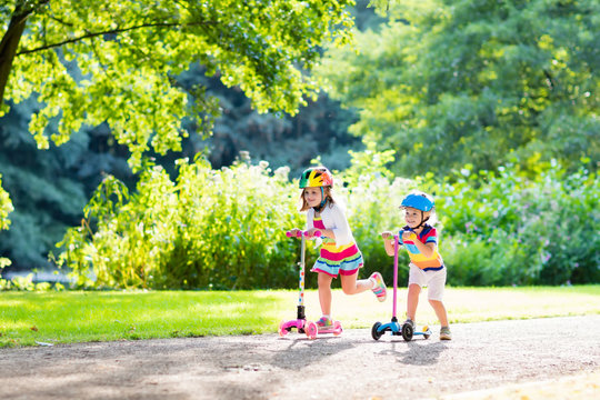 Kids riding scooter in summer park.