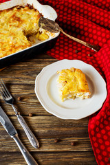 Useful, hearty and delicious dinner or lunch, potato casserole with chicken, cheese, mayonnaise, egg and spices on a wooden background 
