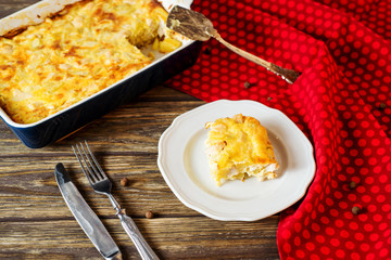 Useful, hearty and delicious dinner or lunch, potato casserole with chicken, cheese, mayonnaise, egg and spices on a wooden background 