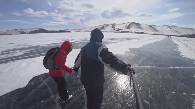 Tourists and travelers on the ice of Lake Baikal skate.