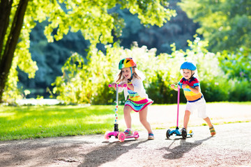Kids riding scooter in summer park.
