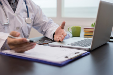 Doctor working a Medical Exam, Healthcare and medically concept,Stethoscope with clipboard and Laptop on desk. Stethoscope on a prescription,test results in background,vintage color,selective focus