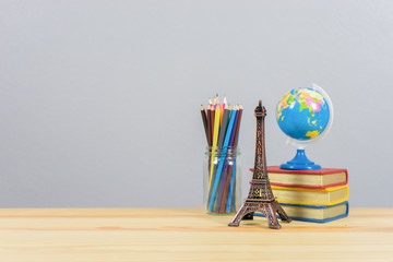 Eiffel tower statue and stack of book and globe on the school desk, book of knowledge school...