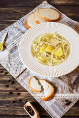 Useful, hearty and healthy lunch, chicken soup with homemade noodles, potatoes, spices and white fresh bread on a wooden background 