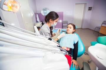 Obraz premium Close-up of pretty little girl opening his mouth wide during treating her teeth by the dentist