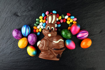 Chocolate Easter bunny and eggs with color ribbon bows on wooden