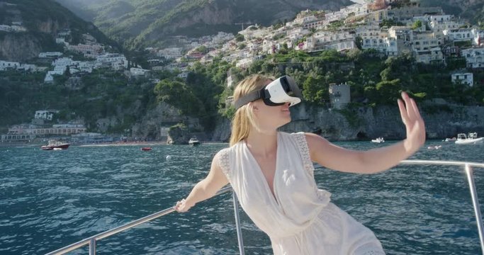 Young woman on sailboat wearing virtual reality headset watching 360 travel video imagination concept enjoying summer vacation Positano Amalfi Coast Italy