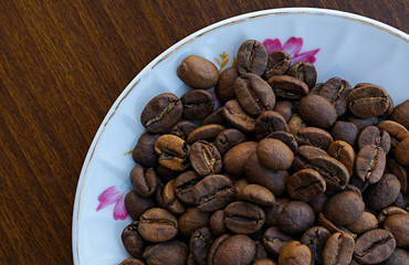 Roasted coffee beans in coffee plate on table