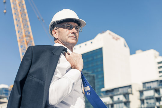Senior elegant builder man in suit at construction site on sunny