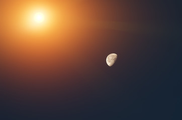 The sun illuminates the moon in the dark sky without stars.