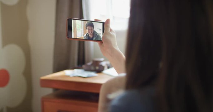 Young woman having video chat holding smartphone  webcam chatting to boy friend at desk in home office