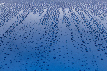 Drops of rain on a blue shiny smooth surface.