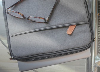 grey laptop case sits on brown table next to old book and notepad and journal ready for digital...