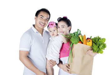 Happy family holds vegetables in studio