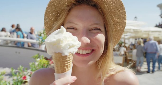Young woman eating ice cream on beach Happy Girl licking Italian Gelato being silly outdoors in summer sunshine enjoying European vacation travel adventure Amalfi Coast Positano Italy