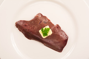 high angle view of  a raw veal liver isolated on white plate with butter and parsley