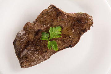 High angle view of a veal liver steack on a white plate