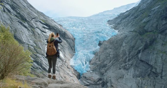 Woman taking photograph of melting glacier with smartphone photographing Climate change concept scenic landscape nature background view enjoying vacation travel trekking adventure