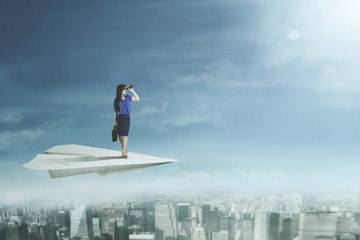 Young businesswoman flying with paper plane