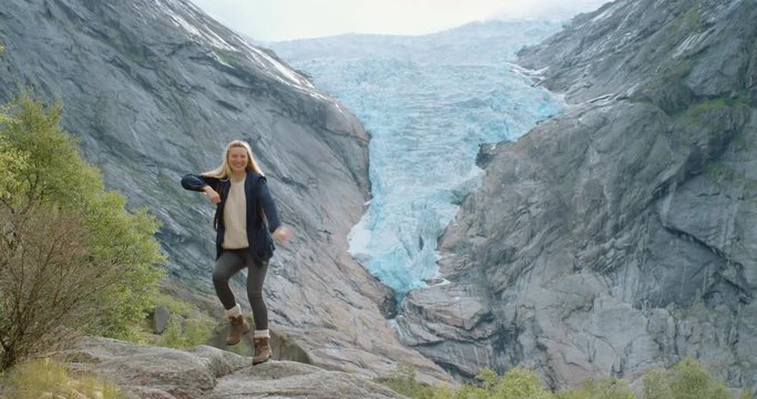 Independent Woman dancing silly freestyle dance outdoors in front of melting glacier Crazy dancer girl having fun enjoying nature celebrating vacation travel adventure Norway
