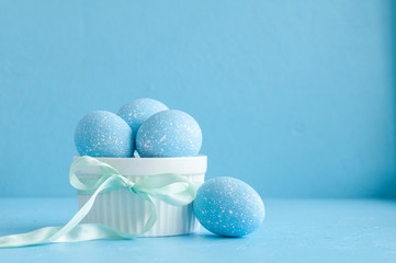 painted Easter eggs in bowl on blue background