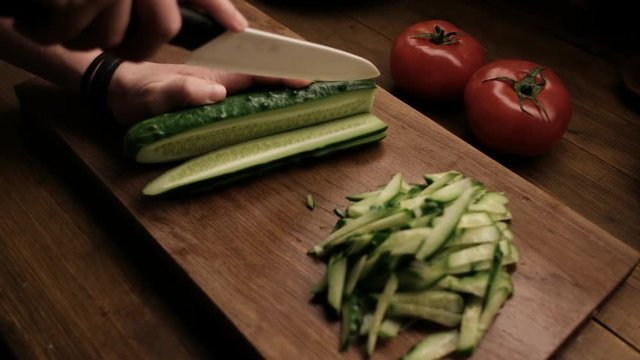 Closeup - Woman Cuts the Cucumber on the Wooden Table Ceramic Knife