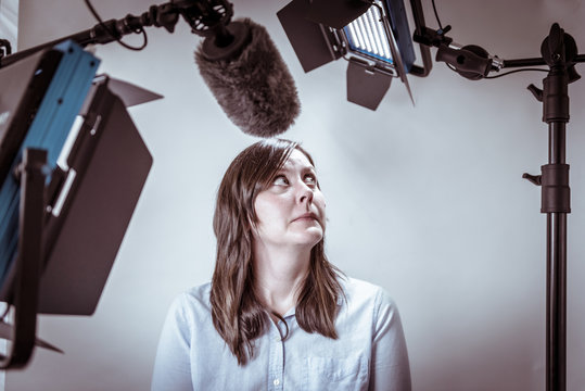 Scared And Nervous Business Woman Under Video Lights And Microphone About To Be Interviewed On Camera.