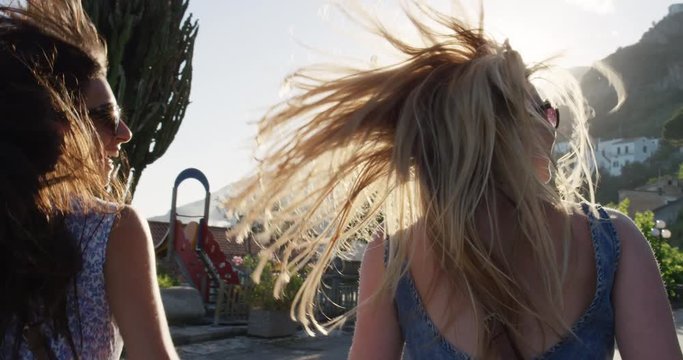 Girl friends balancing on wall and running in Italian street exploring European town at sunset. Best friends having fun enjoying summer vacation travel adventure in SLOW MOTION