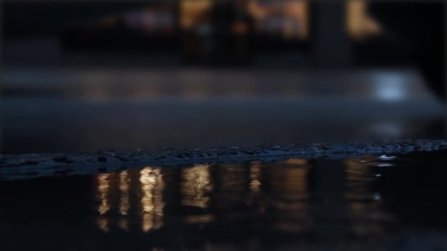 Puddle forming on rainy day in downtown city area with blurry traffic