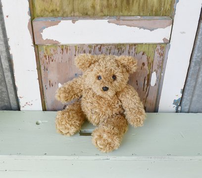 Child's teddy bear toy sitting on a bench.