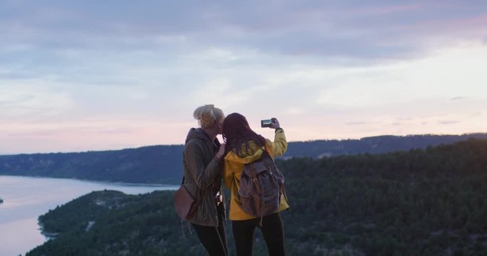 Two girl friends taking photograph smartphone women photographing sunrise landscape nature background view enjoying vacation travel adventure at sunset