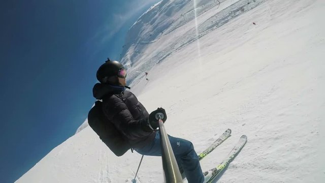Skier on steep ski run on sunny winter day, slow motion first person view