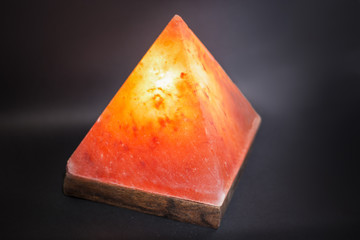 Lamp placed inside of salt stone. Horizontal indoors shot of Himalayan salt pyramid shaped lamp