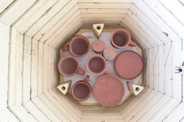 Overhead view of the bottom shelf of a kiln being loaded with pottery for a glaze firing