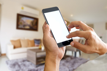 Man hands holding blank screen a smartphone and blurred living room background.