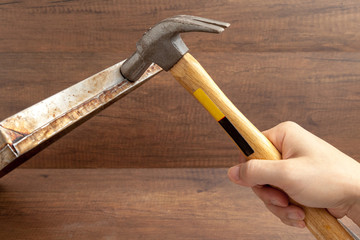 Man handle hammer to hit or fix stainless tray on wooden background.