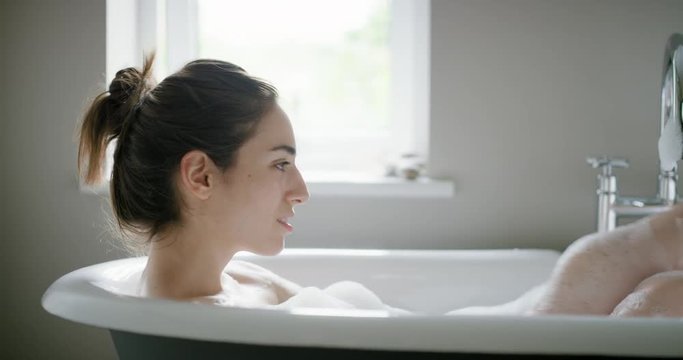 Beautiful Woman lying in bathtub enjoying relaxing bubble bath experiencing mindfulness lifestyle with real natural body care authentic homemade spa treatment