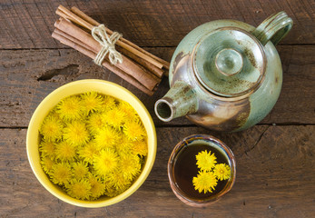 Overhead view of dandelion blossoms in a bowl and dandelion tea in a cup with a tea pot and bundled cinnamon © Kelly
