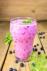 Milkshake with blueberries in glass on wooden table